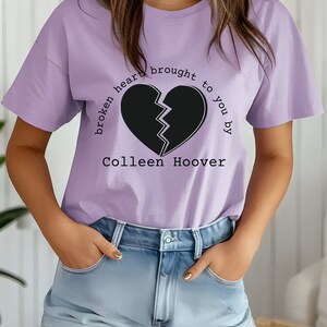 May include: A lavender t-shirt with a broken heart graphic and the text "broken heart brought to you by Colleen Hoover".