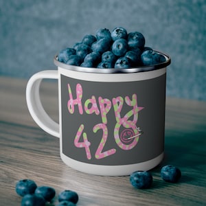 May include: A white enamel mug with a gray background and pink and green polka dots. The mug says "Happy 420" with a smiley face and a joint.