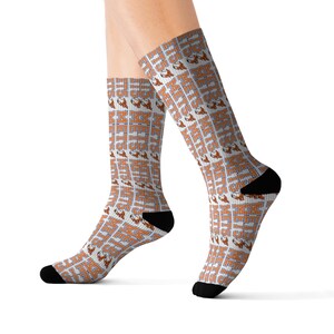 May include: White socks with an all-over pattern of the word "METS" in orange block letters and a baseball graphic. The socks have black heels and toes. The socks are knee-high.