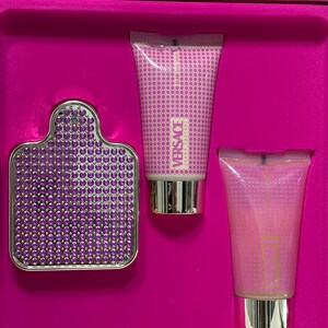 Op de afbeelding: Een roze geschenkdoos met een Versace geurset. De set bevat een fles parfum, een bodylotion en een douchegel. Alle drie producten hebben een paars en gouden ontwerp.