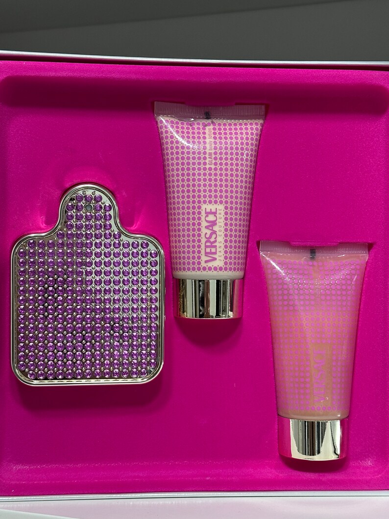 Op de afbeelding: Een roze geschenkdoos met een Versace geurset. De set bevat een fles parfum, een bodylotion en een douchegel. Alle drie producten hebben een paars en gouden ontwerp.