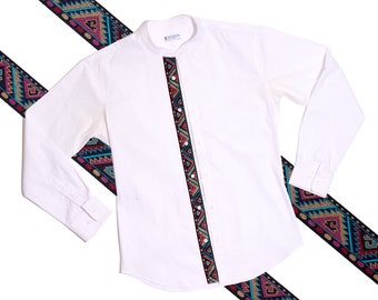 May include: White long-sleeve shirt with a colorful geometric pattern down the front. The pattern is a black, blue, pink, and gold design.