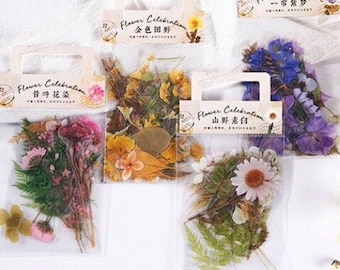 May include: Four small bags of dried flowers and leaves. Each bag has a label with the words "Flower Celebration" and a Chinese character. The bags are on a white surface.