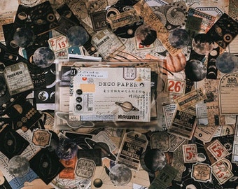 Può includere: Una collezione di adesivi in ​​carta in stile vintage con disegni celesti e spaziali. Gli adesivi sono stampati su carta marrone con inchiostro nero e presentano pianeti, stelle e altri corpi celesti. Gli adesivi sono perfetti per aggiungere un tocco di fantasia a diari, pianificatori e altri lavoretti di carta.