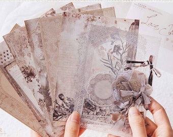 Könnte beinhalten: Eine Sammlung von Papier-Ephemera im Vintage-Stil mit Spitzenbesatz und dekorativen Elementen. Die Papiere zeigen florale, Steampunk- und Spitzenmuster in neutralen Farbtönen. Einige Papiere befinden sich in einer Klarsichttüte mit dem Text "Lace Cobalt".