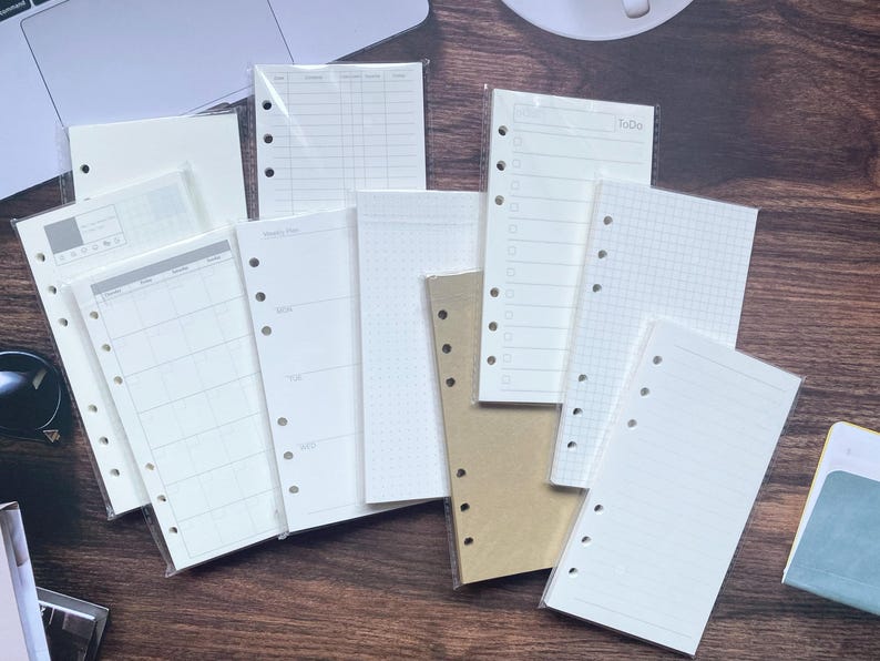 Pu&ograve; includere: Una collezione di pagine di ricarica in carta bianca, bianca e marrone per un raccoglitore a 6 anelli. Le pagine hanno diversi layout, tra cui rigato, grigliato e vuoto.