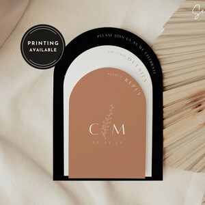 May include: A wedding invitation with a modern arch design. The invitation is printed on three layers of cardstock in black, white, and brown. The invitation features the couple's initials "CM" and the wedding date "09.21.21". The text "Please join us as we celebrate" and "Kindly Reply" is also included.