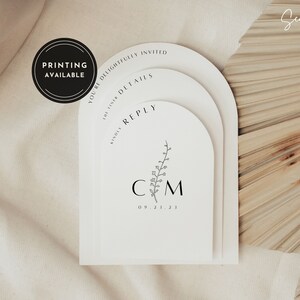 May include: A white arch-shaped wedding invitation with the text "You're delightfully invited" and "Kindly reply" on the top two arches. The bottom arch has the initials "C M" and the date "09.21.23" with a small floral design.