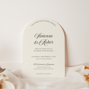 May include: An ivory wedding invitation with an arched top, featuring the names "Vivienne & Asher" in elegant script. The invitation includes the wedding date, time, and venue details. Dried floral accents are visible.