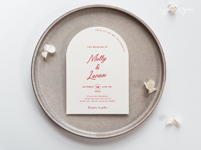 May include: A wedding invitation with a cream background and red text. The invitation is shaped like an arch and reads "Join us as we celebrate the wedding of Molly & Lenox, October 16, 2024, 4:00 PM, Riverside Meadows, 2436 Spring Trail Drive, Asheville, North Carolina 28801, Reception to follow."