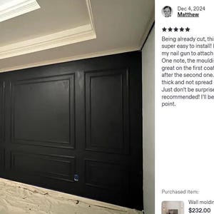 May include: A wall featuring black rectangular moulding panels installed in a grid pattern. A blue step ladder stands in the foreground. The wall is painted a solid matte black, creating a framed panel effect across the entire surface area.
