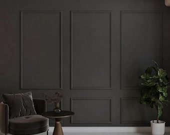 May include: A dark charcoal gray wall with rectangular molding panels, a matching velvet armchair, a small round side table with a dark glass vase containing dried branches, and a green potted plant in a white ceramic pot.