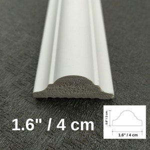 May include: A white decorative molding strip with a curved profile. The cross-section shows a width of 1.6 inches and a height of 0.8 inches. The piece features a smooth finish and a textured base, clearly displaying its dimensions in inches.