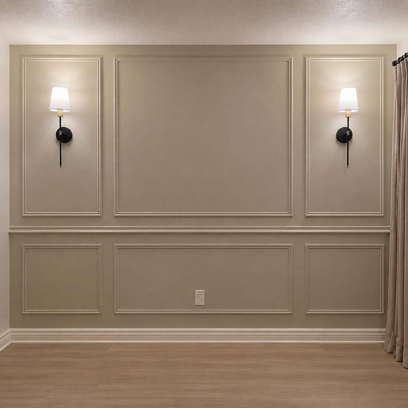 May include: A beige wall featuring decorative rectangular molding panels arranged in a grid pattern. Two wall-mounted light fixtures with black metal arms and white fabric shades are positioned symmetrically on the upper side panels of the wall.