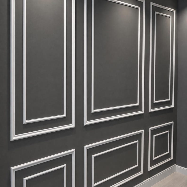 May include: A dark gray wall featuring white rectangular molding panels arranged in a grid pattern. The wall surface is smooth and matte, while the raised white trim creates a structured, geometric design across the entire vertical surface.