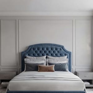 May include: A blue tufted headboard with a curved top edge, featuring a button-tufted design. The bed is dressed with white linens, two light gray pillows, two dark gray rectangular pillows, and one small rectangular brown accent pillow.