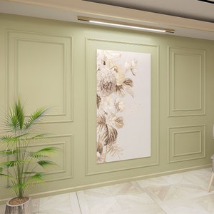 Puede incluir: Una pieza de arte mural rectangular que presenta un arreglo floral vertical en tonos beige, crema y marr&oacute;n. La obra se exhibe en una pared verde salvia con paneles de molduras rectangulares, situada bajo una l&aacute;mpara horizontal.