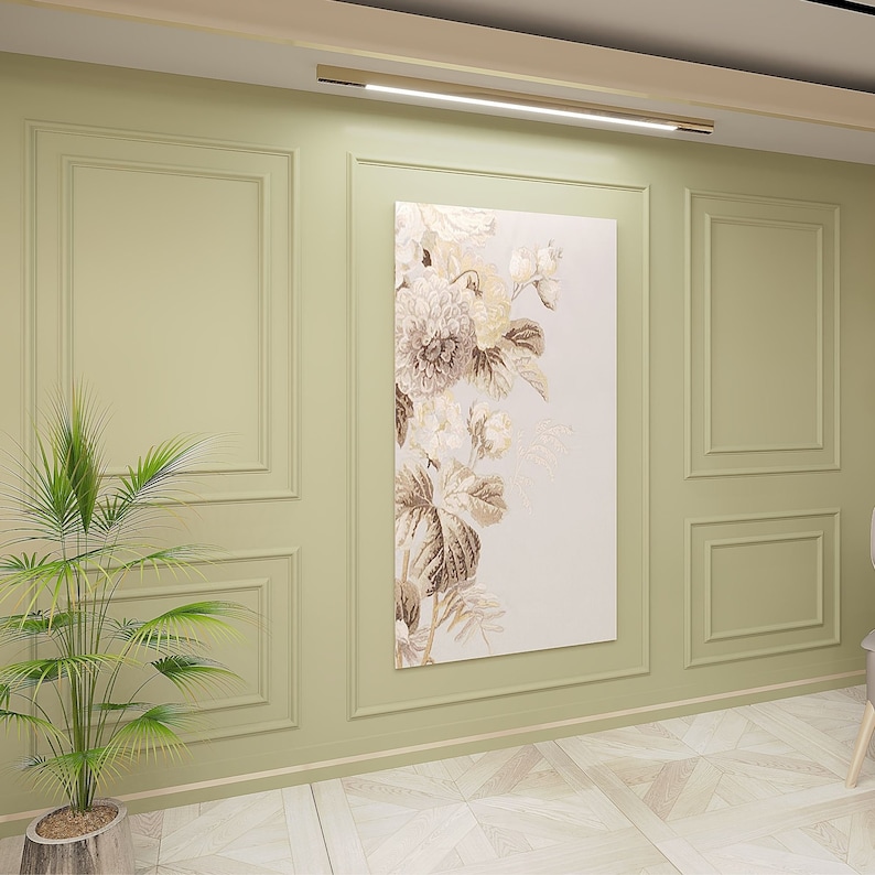 Puede incluir: Una pieza de arte mural rectangular que presenta un arreglo floral vertical en tonos beige, crema y marr&oacute;n. La obra se exhibe en una pared verde salvia con paneles de molduras rectangulares, situada bajo una l&aacute;mpara horizontal.