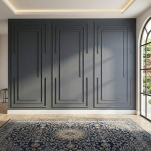 Op de afbeelding: Een donkergrijze muur met drie rechthoekige panelen met verhoogde sierlijsten. De muur bevindt zich boven een lichte houten vloer bedekt met een groot, ingewikkeld marineblauw en beige patroonkleed met een centraal medaillonontwerp.