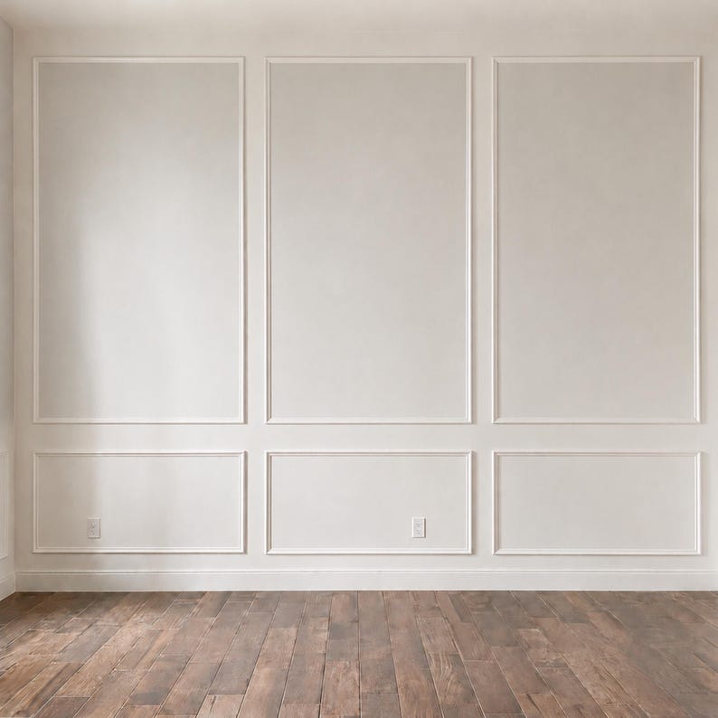 May include: A wall featuring white wainscoting with three large rectangular upper panels and three smaller rectangular lower panels. The wall is painted a solid off-white color and includes two electrical outlets. The floor is dark brown wood.