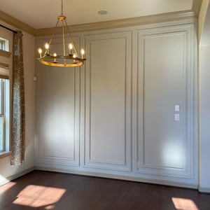 Pu&ograve; includere: Un muro bianco con un pannello decorativo. La parete ha un lampadario dorato appeso al soffitto.