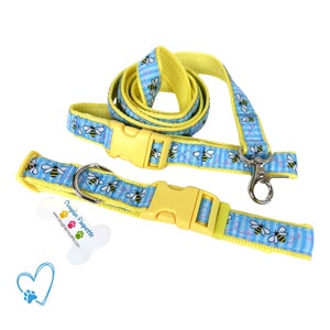 May include: A yellow and blue dog collar and leash set. The collar and leash feature a repeating pattern of bees on a blue striped background. The set includes a yellow plastic buckle and a metal clasp.