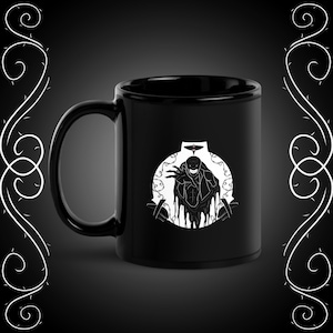 Może przedstawiać: Czarny ceramiczny kubek do kawy z białym nadrukiem przedstawiającym postać w cieniu z złowrogim uśmiechem, otoczoną winoroślą. Postać ma na głowie hełm z czerwonym symbolem.
