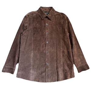 May include: A brown suede jacket with a button-down front and a collared neckline. The jacket has long sleeves and a slightly worn appearance. The overall style is casual and suitable for various occasions.
