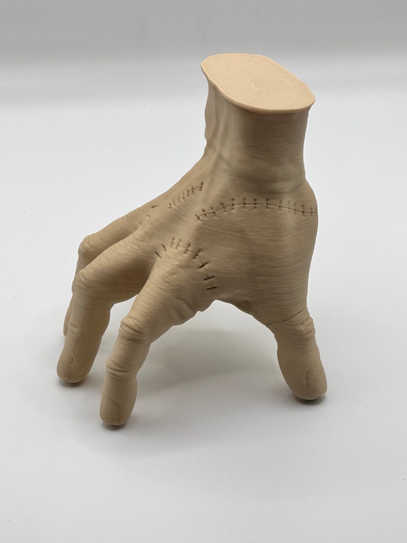 Puede incluir: Una mano beige impresa en 3D con costuras. La mano est&aacute; en posici&oacute;n con los dedos extendidos y ligeramente curvados.