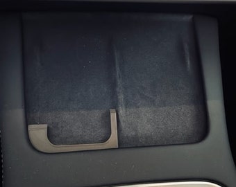 Puede incluir: Un interior de coche negro con un compartimento de almacenamiento con una manija extraíble.