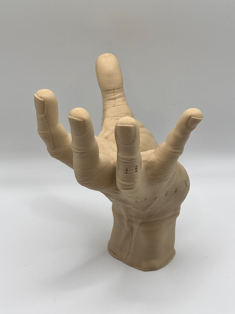 Puede incluir: Una escultura beige con forma de mano con texturas detalladas de los dedos y la palma. La escultura est&aacute; hecha de un material liso y mate y parece estar hecha de un tipo de resina.