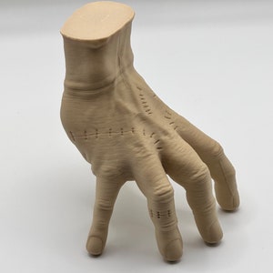 Puede incluir: Una mano esculpida de color beige con detalles cosidos. La mano est&aacute; posada con los dedos extendidos y ligeramente curvados. La mano est&aacute; hecha de un material liso y texturizado.