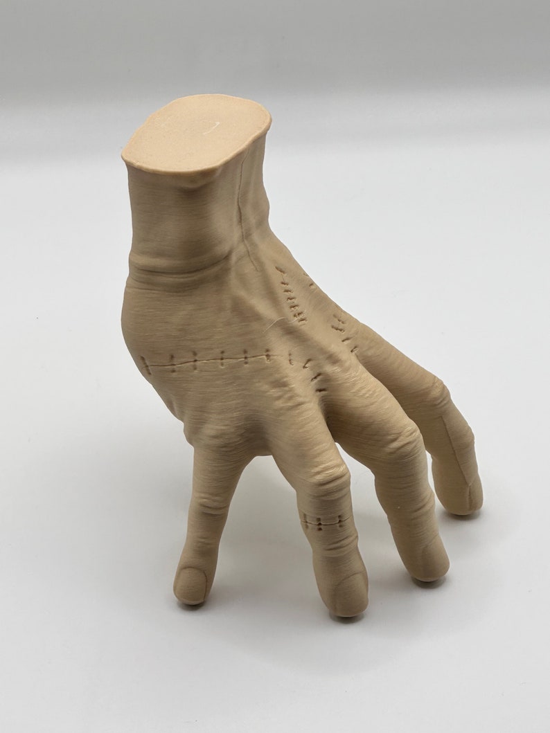Puede incluir: Una mano esculpida de color beige con detalles cosidos. La mano est&aacute; posada con los dedos extendidos y ligeramente curvados. La mano est&aacute; hecha de un material liso y texturizado.