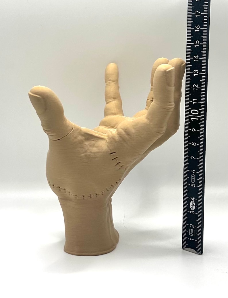 Puede incluir: Una mano beige impresa en 3D con costuras cosidas, que se muestra junto a una regla que mide 25,4 cm.