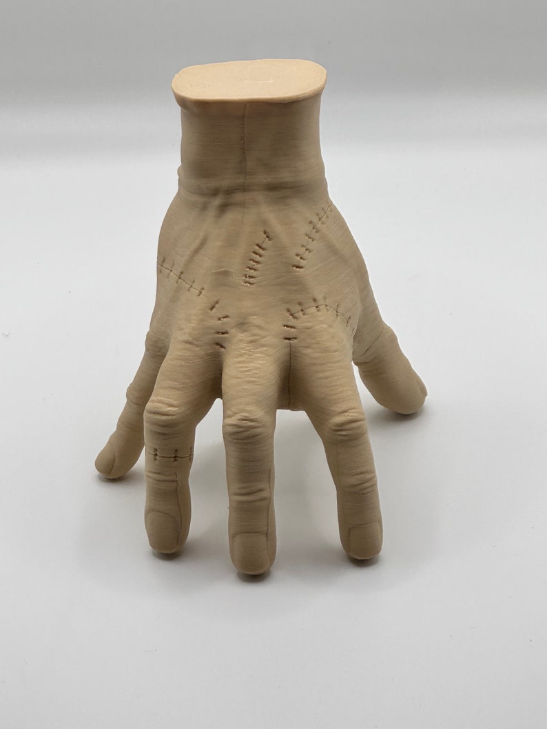 Puede incluir: Una mano esculpida de color beige con costuras cosidas en los dedos y la palma. La mano est&aacute; posada con los dedos extendidos y ligeramente curvados.