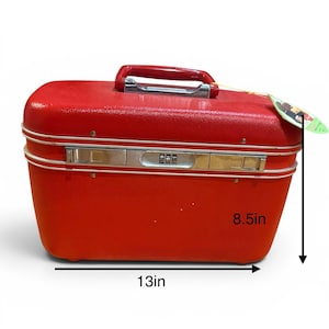 May include: A bright red hard-shell travel case with a textured finish, a red top handle, and silver-tone metal hardware including a combination lock. The case measures 13 inches in width and 8.5 inches in height as indicated by the visible labels.