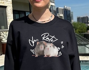 May include: Black sweatshirt with the text "Oh Rats!" and an illustration of two rats. The design includes white hearts. The person in the image is wearing black shorts and sunglasses.