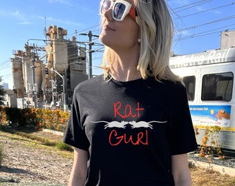 May include: A black t-shirt with a white graphic of two rats facing each other. The text "Rat Gurl" is written in red above the rats.
