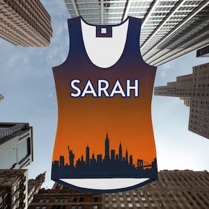 May include: A sleeveless vest top with a skyline design. The top features the name "SARAH" in white block letters. The design includes a silhouette of the New York City skyline against an orange and blue gradient background.
