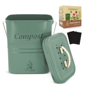 May include: A sage green metal kitchen compost bin with a matching lid, featuring the word Compost in script and a Fern & Maple Home logo. The set includes a gold-toned handle, a ventilated lid with a gold knob, and three black charcoal filters.