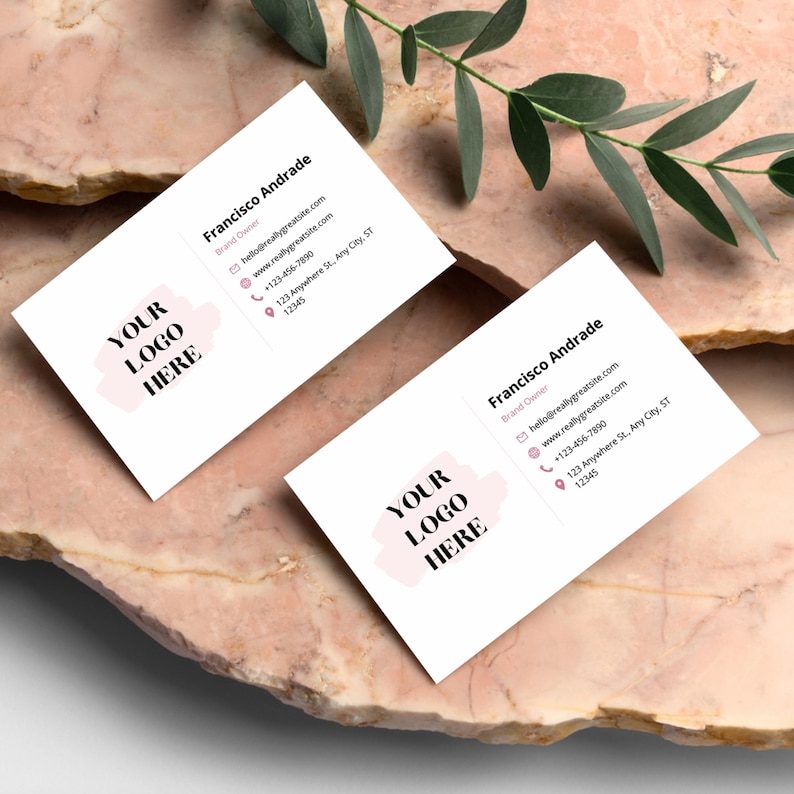 May include: Two white business cards with a pink logo placeholder that says "YOUR LOGO HERE". The text on the cards reads "Francisco Andrade, Brand Owner, hello@reallygreatsite.com, www.reallygreatsite.com, +123-456-7890, 123 Anywhere St., Any City, ST, 12345".