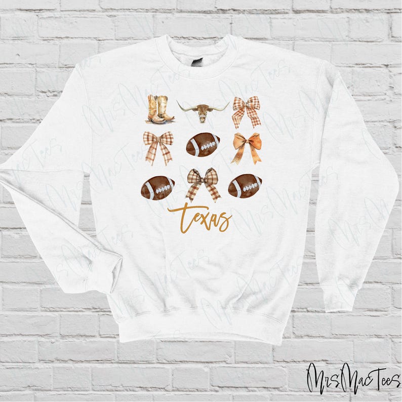 May include: White sweatshirt with a brown and white football, a brown and white bow, a brown and white steer head, and the word "Texas" in gold lettering.