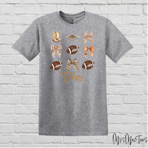 May include: Gray t-shirt with a design featuring a football, a cowboy boot, a bow, and the word "Texas".