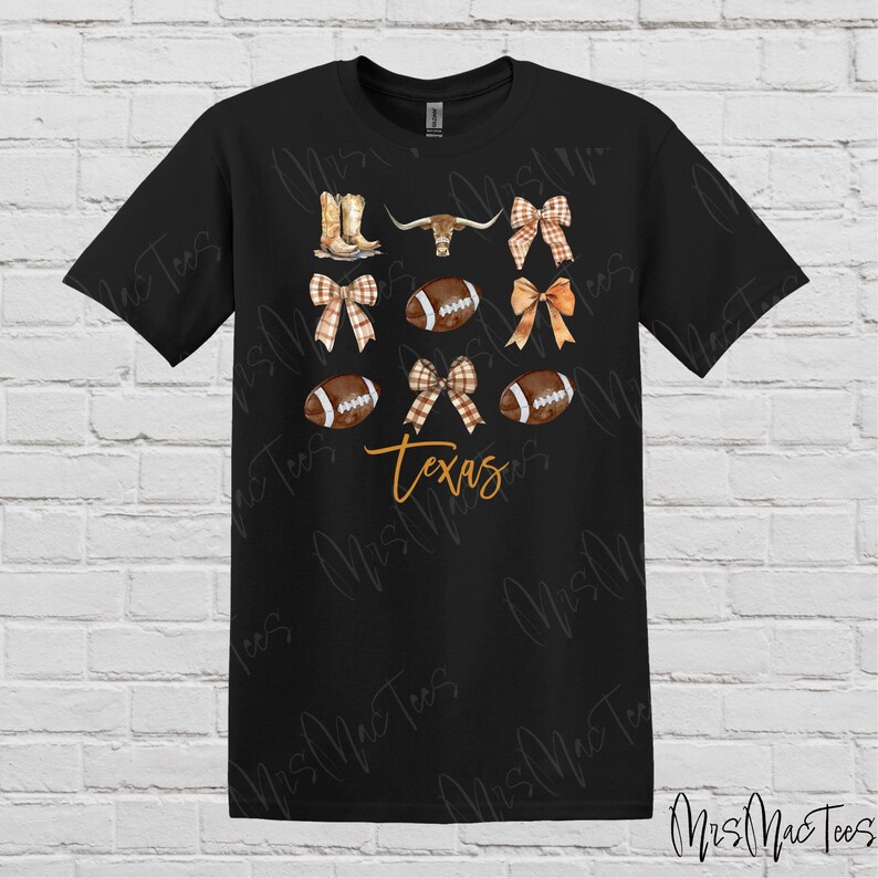 May include: Black t-shirt with a design featuring footballs, bows, cowboy boots, and a longhorn steer. The text "Texas" is printed in orange on the shirt.