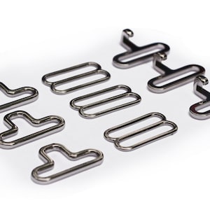 May include: A set of silver metal bra strap adjusters and hooks. The adjusters are double-looped and the hooks have a T-shape.