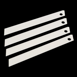 May include: Four white plastic utility knife blades with a hole at the top of each blade.