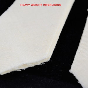 Puede incluir: Primer plano de varias piezas de tela blanquecina, posiblemente entretela, con el texto "HEAVY WEIGHT INTERLINING" en rojo. La tela tiene un tejido texturizado y bordes deshilachados, lo que sugiere un material de costura.