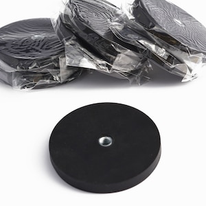 May include: Black round magnets with a threaded insert. Several are packaged in clear plastic. The magnets are circular and appear to be made of rubber or a similar material. The background is white.