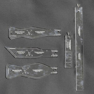 Peut inclure: Ensemble d'outils de quilting en acrylique transparent, comprenant des formes variées et une longue règle. Les outils comportent des marquages de mesure et le texte "THACKERY TAILORING TOOLS". La règle mesure environ 30 cm.