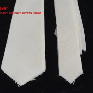 May include: Two pieces of white heavy weight interlining fabric, each measuring 2 5/8 inches wide. The fabric is folded in half and the edges are frayed.